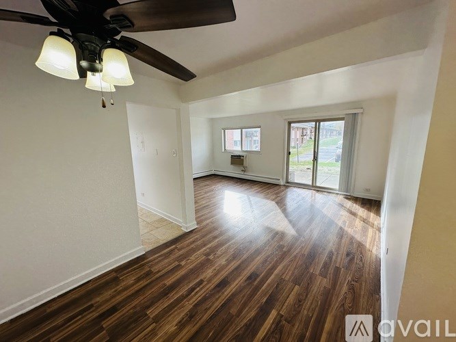 A room with a ceiling fan and wooden flooring.