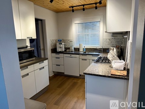 A kitchen with white cabinets and a wooden ceiling.