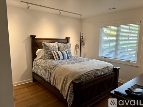 A bedroom with a large bed and a window with blinds.