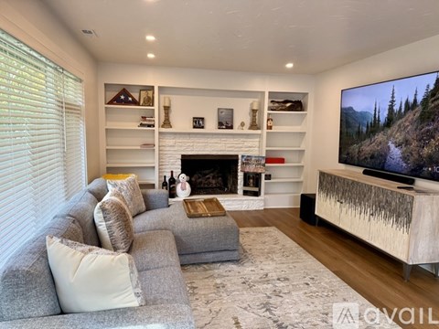 A living room with a grey couch, a fireplace, and a television.