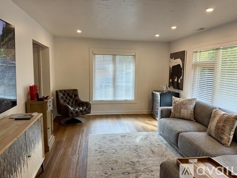 A living room with a grey couch, a brown armchair, and a wooden cabinet.