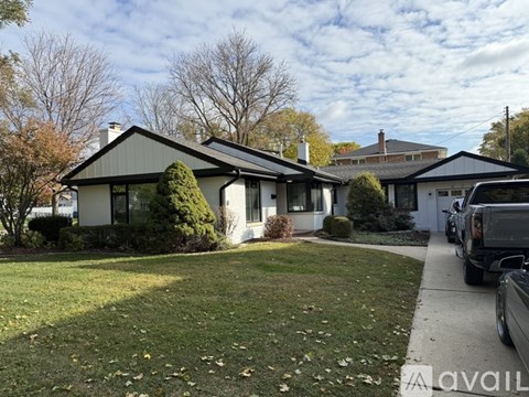 A house with a green lawn and a tree in front.