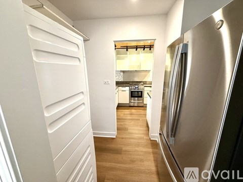 A kitchen with a refrigerator on the right and a white door on the left.
