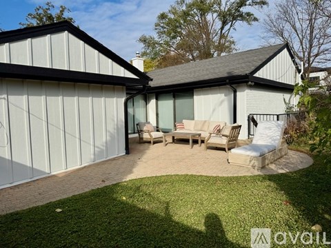 A backyard with a patio and a white house.