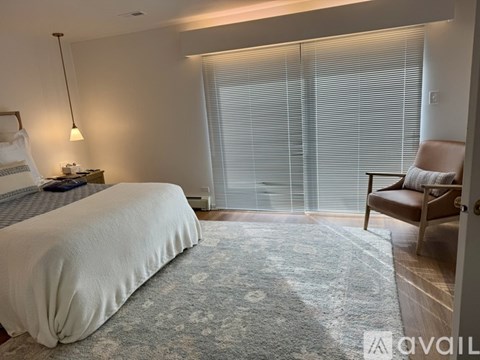 A bedroom with a large bed, a chair, and a rug.