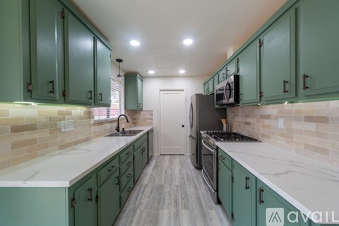 A kitchen with green cabinets and a white countertop.