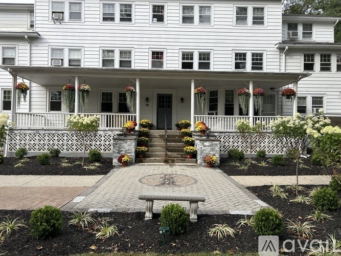 A white house with a front porch and a circular walkway in front.