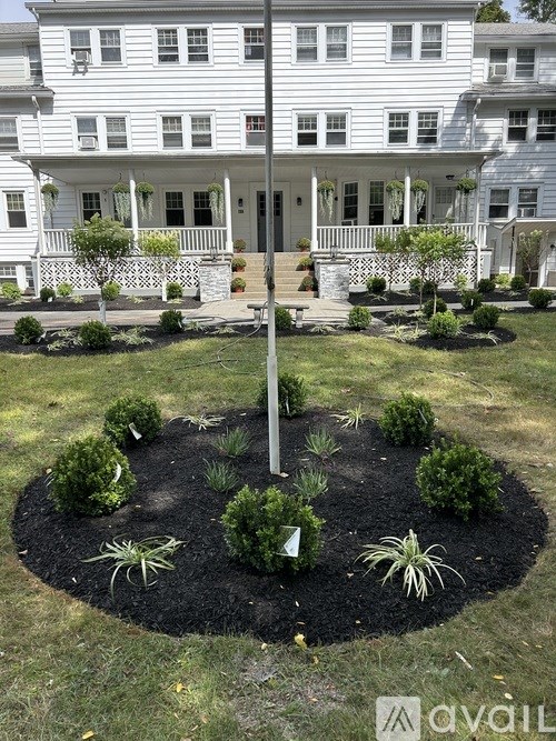 A white house with a circular garden in front.