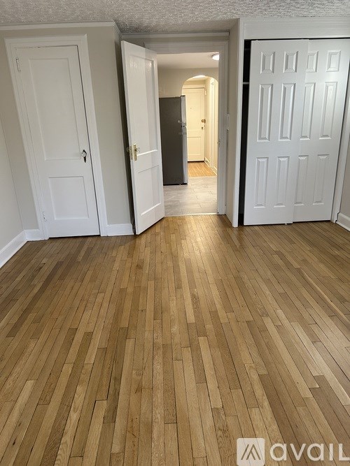 A room with wooden flooring and two white doors.