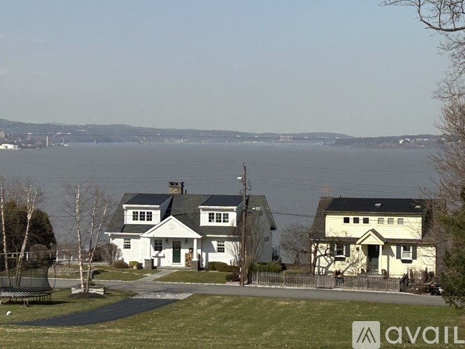 A house with a white facade is situated by a body of water.