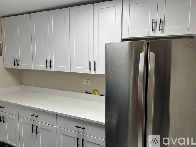 A kitchen with white cabinets and a stainless steel refrigerator.