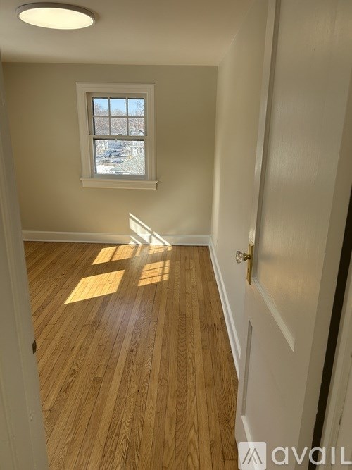 A room with wooden floors and a window letting in sunlight.