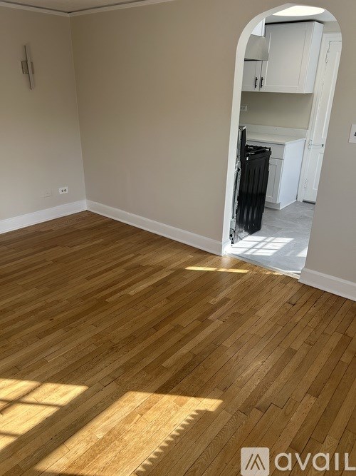 A room with wooden flooring and a white doorway leading to another room.