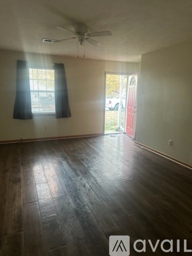 A room with a ceiling fan and a window with black curtains.