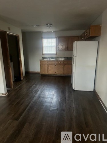 A kitchen with wooden floors and a white refrigerator.