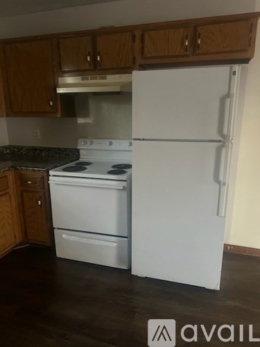 A white refrigerator stands in a kitchen with wooden cabinets.