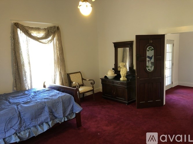 A bedroom with a bed, chair, and cabinet.