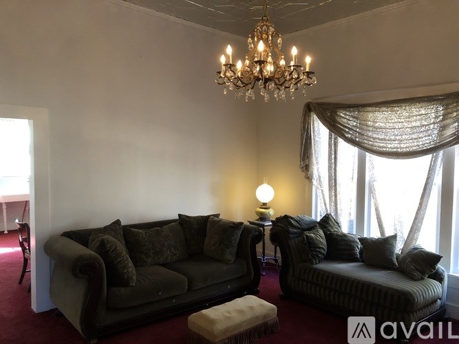 A living room with a grey couch and a chandelier.