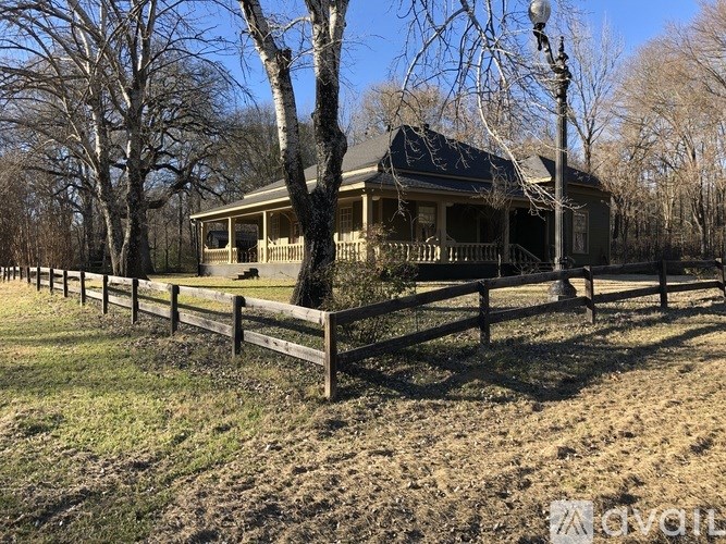 A house with a porch and a fence in front of it.