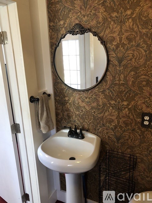 A bathroom with a brown patterned wallpaper and a white sink.