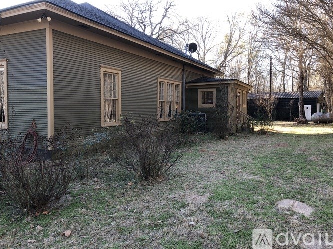A house with a grey siding and a brown roof with a satellite dish on top.
