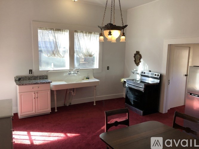 A kitchen with a sink, stove, and cabinets.