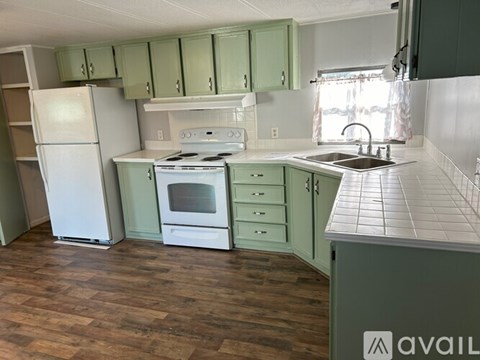 A kitchen with green cabinets and a white fridge.