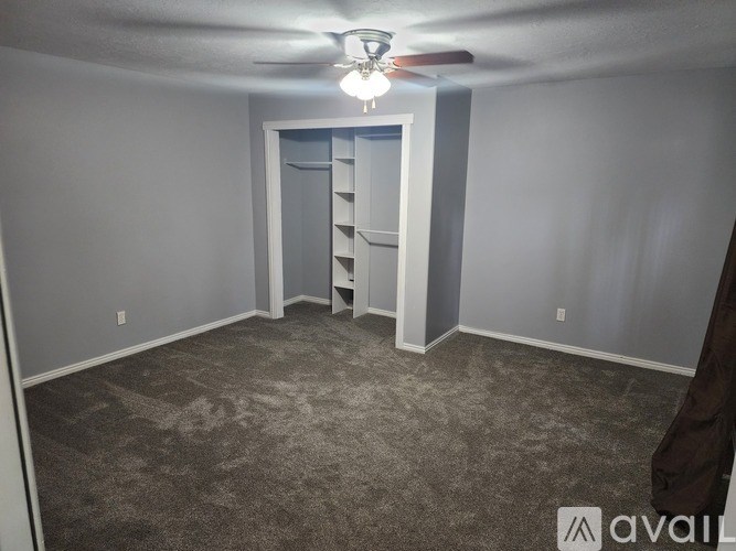 A room with a carpeted floor and a ceiling fan.