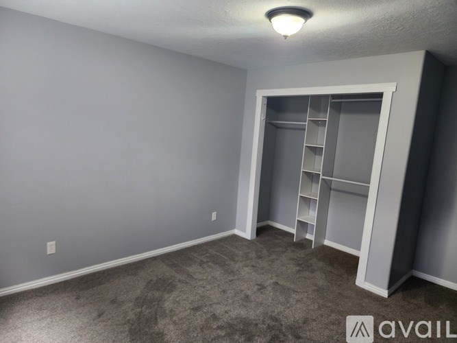 A room with a grey carpet and a grey wall with a white door.