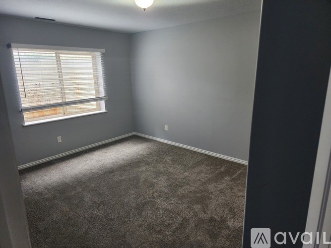 A room with a carpeted floor and a window with blinds.