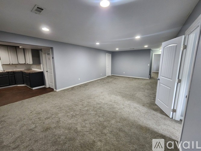 A spacious room with a carpeted floor and white walls.