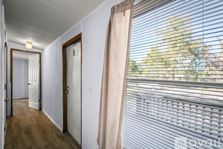 A hallway with a window covered by blinds.