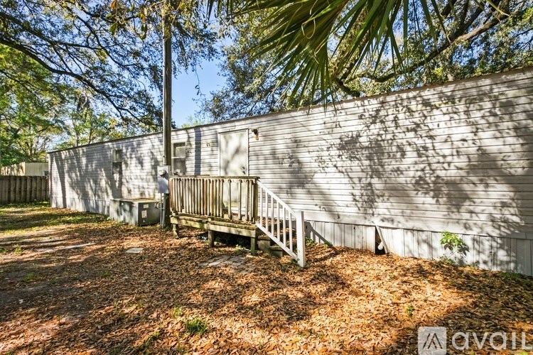 A wooden deck with a railing is in front of a grey wall.