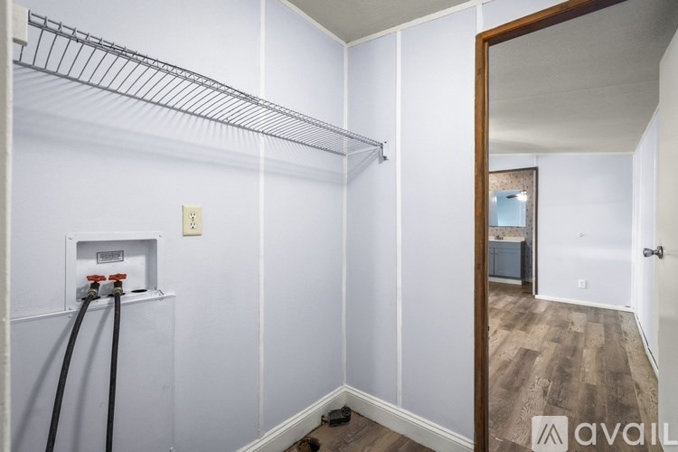 A white wall with a shelf and a mirror on the right side.