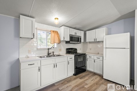 A kitchen with white cabinets and appliances.