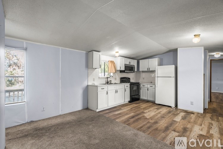 A kitchen with white appliances and wooden floors.