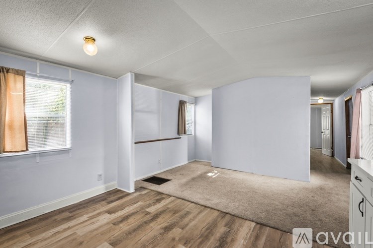 A spacious room with wooden flooring and white walls.