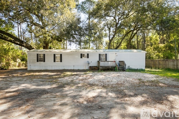A white house with a gravel driveway in front of it.