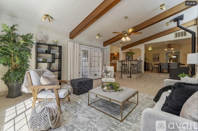 A living room with a grey couch, a wooden chair, and a glass coffee table.