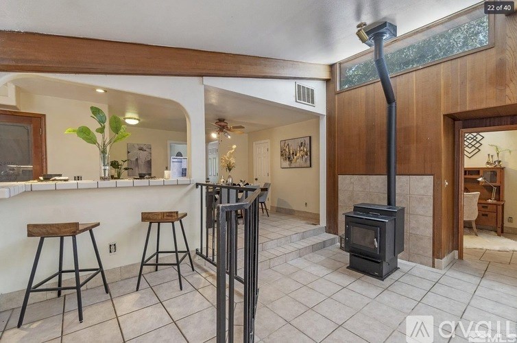 A wood stove is in a living room with a tile floor.