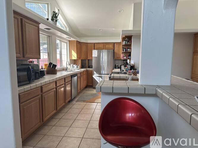 A kitchen with a red chair in the middle.