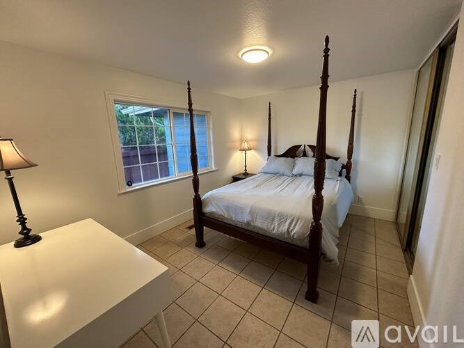 A bedroom with a four poster bed and a window.
