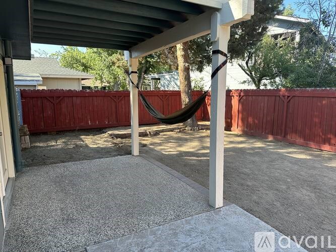 A patio with a hammock and a gravel ground.