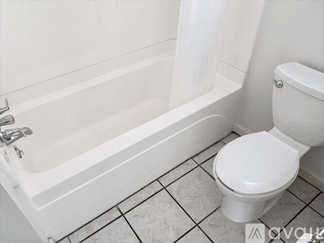 A white toilet sits next to a white bathtub in a bathroom.