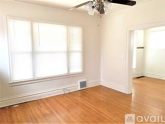 A room with a ceiling fan and a window with blinds.