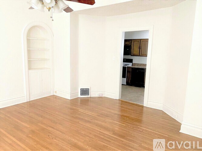 A room with a fan and a doorway leading to another room.