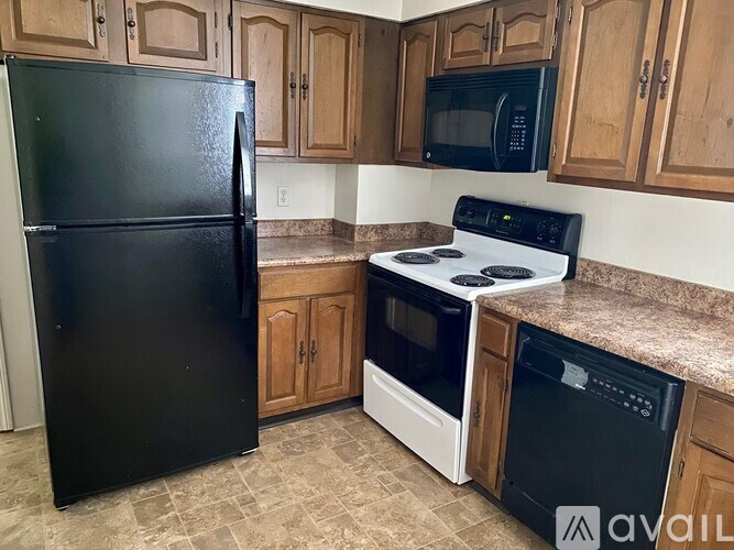 A kitchen with a black fridge, white oven, and black microwave.