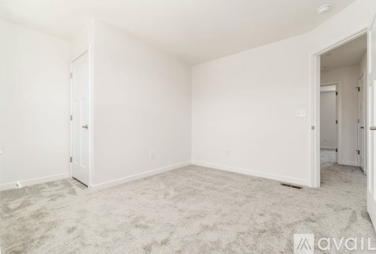 A spacious room with white walls and carpeted floor.
