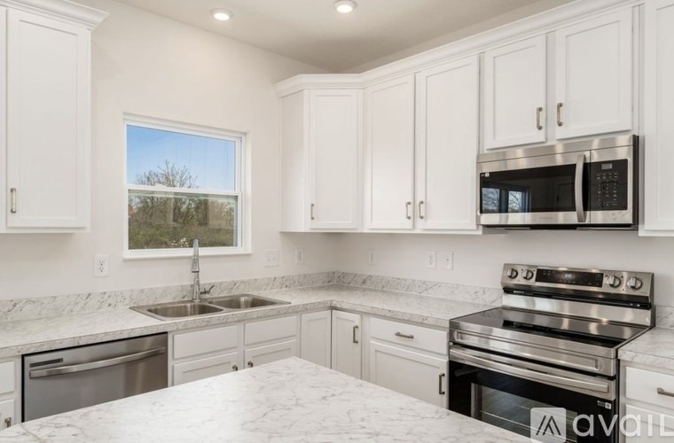 A kitchen with white cabinets and a marble countertop.