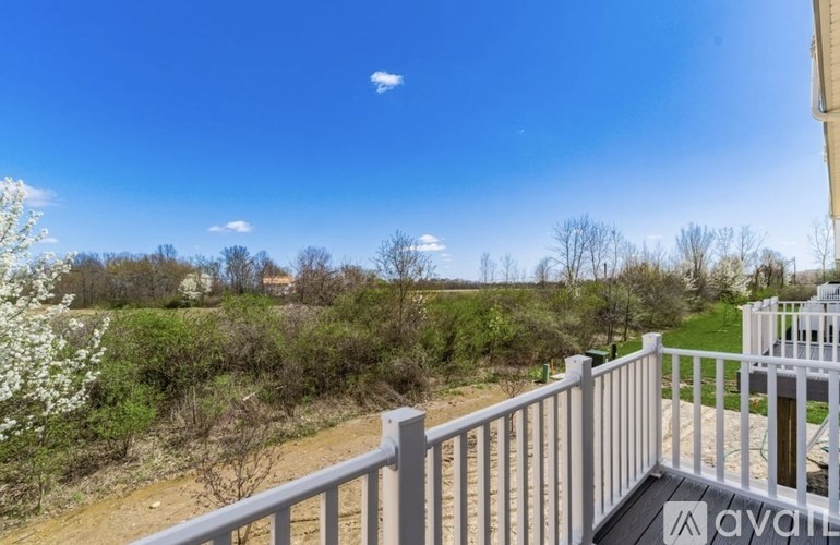 A balcony overlooks a field with trees and a house in the distance.